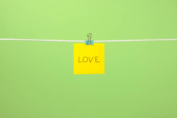 istock Yellow paper note on clothesline with text Love over colorful background 879735842