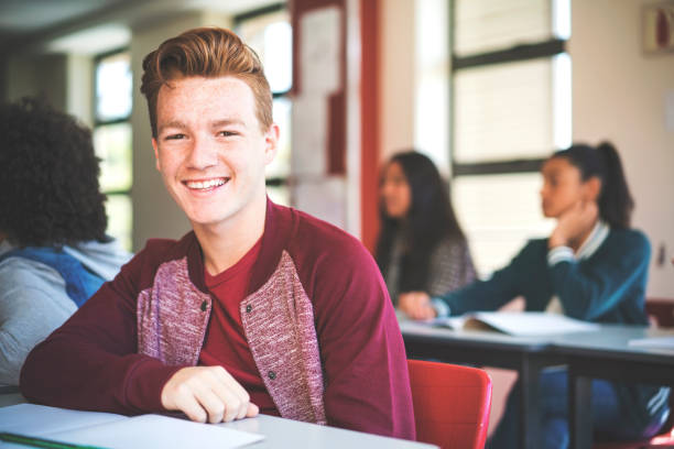 istock Smiling redhead teenage student sitting at school 879740842