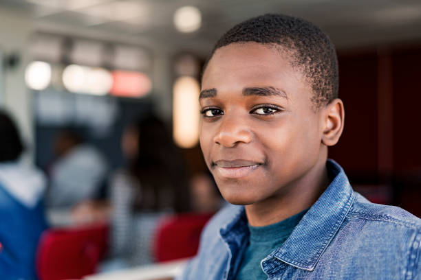 Close-up of confident male teenage student Close-up of confident teenage boy at high school. Portrait of male student is with short black hair in classroom. He is wearing blue denim. teenage boys stock pictures, royalty-free photos & images