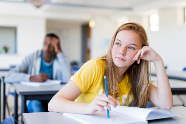 Thoughtful female teenage student leaning on desk