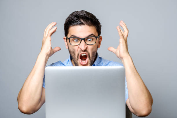 Portrait of amazed man with laptop computer over gray background