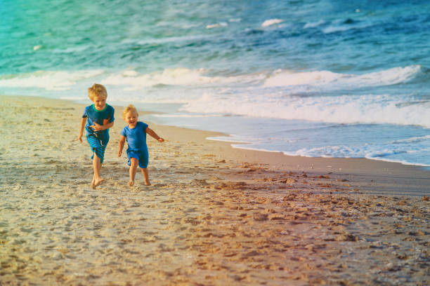 istock little boy and girl run play at beach 879751564