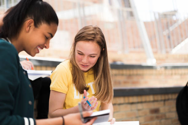 istock Cheerful female teenage students sitting with book 879751870