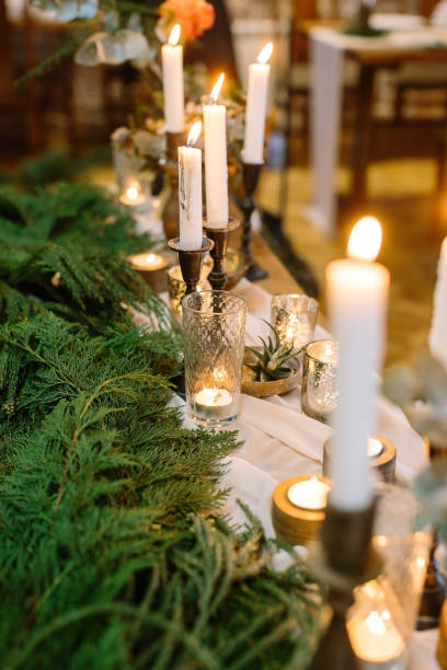 istock new year, interior design, winter concept. long table for celebrating decorated with numerous of shining candles in tall holders and in faceted thick wall flasses, they are standing by green branches 879754368