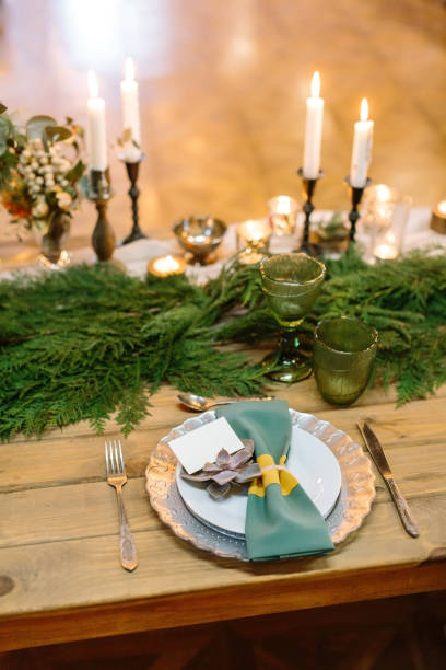 istock romance, dining, celebration concept. on the wooden table that covered conifers branches there are royal setting composed of dishes, silverware and numerous burning candles 879759720