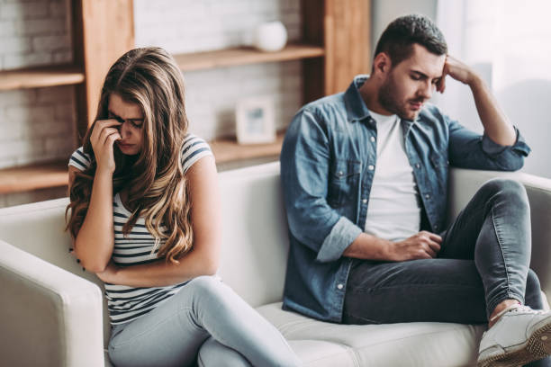 Upset couple at home. Upset couple at home. Handsome man and beautiful young woman are having quarrel. Sitting on sofa together. Family problems. breaking up stock pictures, royalty-free photos & images