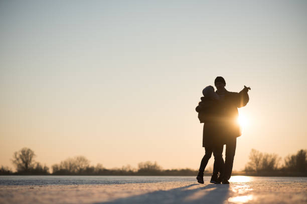 Romantic couple dancing on frozen lake Couple dance together on frozen lake at sunset - winter scene middle aged couple dancing stock pictures, royalty-free photos & images