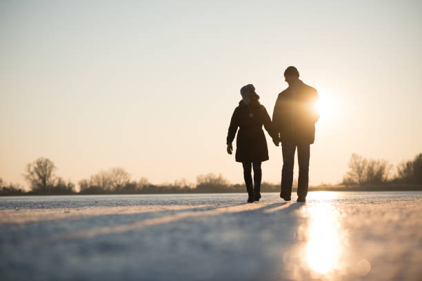 amour couple marchant tout en la tenant par la main - ice winter white women photos et images de collection