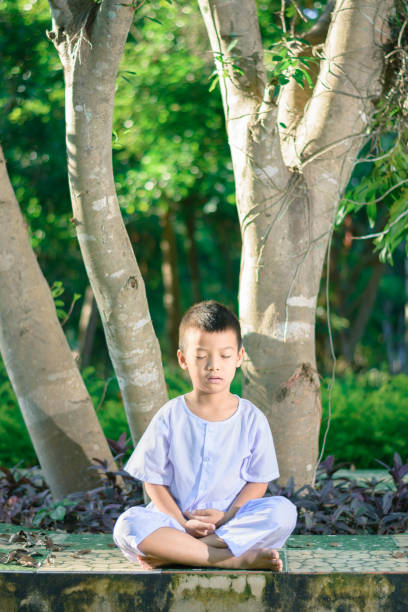 istock kid on white clothing , practice sitting Meditation under the big tree with peace in mind 879766740