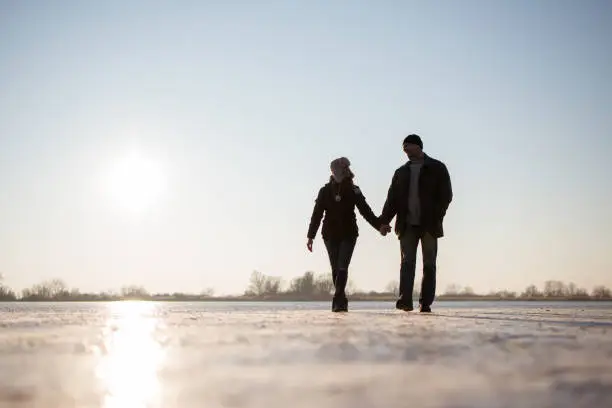 Happy winter couple walking together on frozen lake