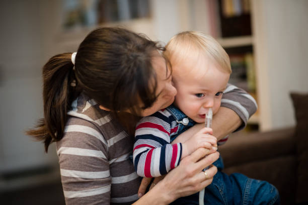 Woman using nasal aspirator for baby Nose hygiene of a baby boy being done by mother flared nostril photos stock pictures, royalty-free photos & images