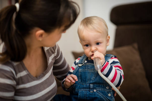 Baby cleaning his nose under supervision of mother Mother helping kid clean nose mucus with a nasal aspirator flared nostril photos stock pictures, royalty-free photos & images