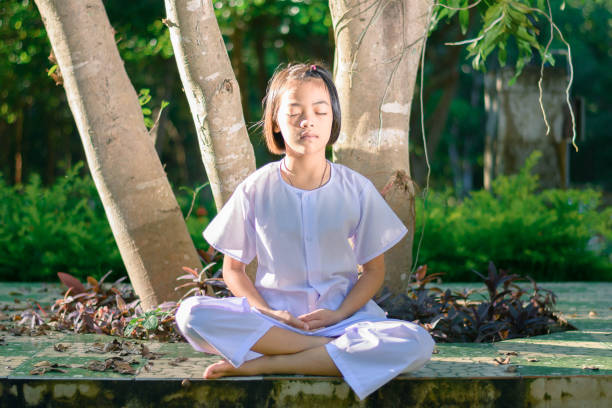 istock kid on white clothing , practice sitting Meditation under the big tree with peace in mind 879770812