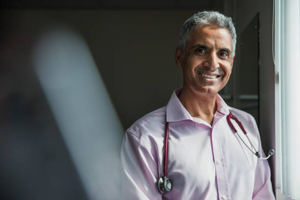 Portrait of a Doctor Portrait of a mature Asian doctor smiling at the camera. doctor general practitioner stock pictures, royalty-free photos & images