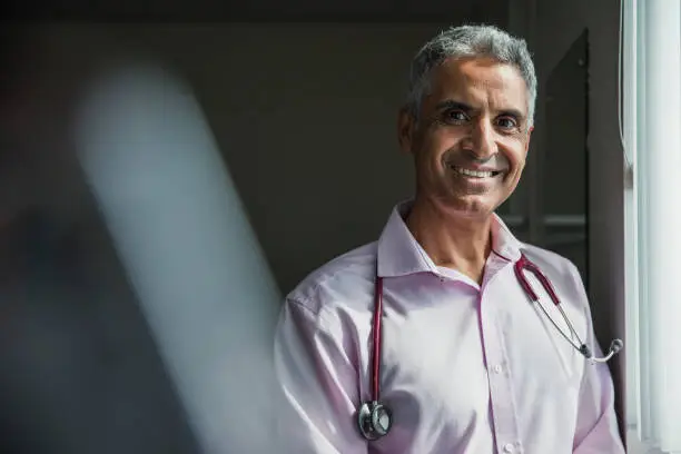 Portrait of a mature Asian doctor smiling at the camera.