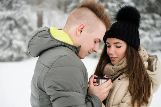 Couple sharing hot coffee. Winter background.