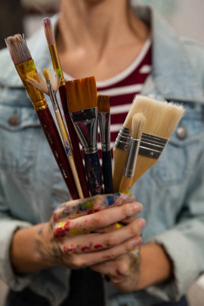 istock Woman holding various brushes in drawing class 879788204