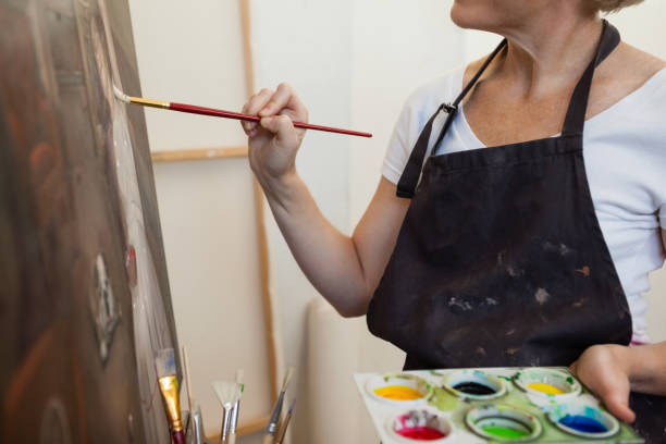 istock Woman painting on canvas in drawing class 879788448