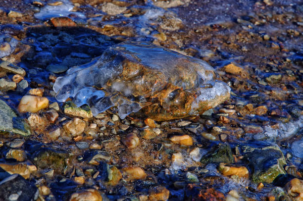 istock a rock covered with ice on the shore of a freezing river 879792268