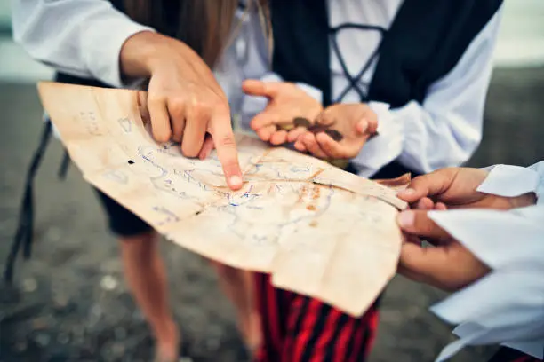 Three little pirates, a girl aged 11 and two boys aged 7 are playing pirates on the beach. They are trying to read ancient treasure map that leads to ... a treasure. The map is hand drawn by the autor of the photo.
