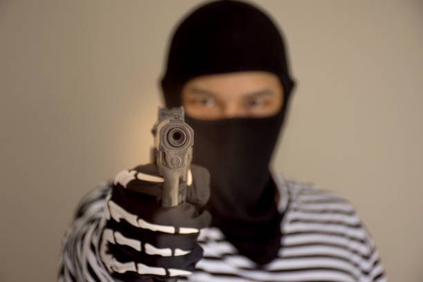 istock The terrorists aiming his weapon under the mask with the blurry face behind 879802158