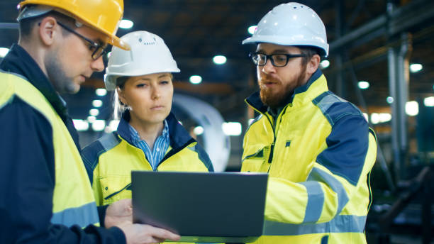 istock Male and Female Industrial Engineers Talk with Factory Worker while Using Laptop. They Work at the Heavy Industry Manufacturing Facility. 879813880