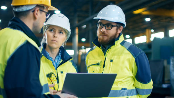 istock Male and Female Industrial Engineers Talk with Factory Worker while Using Laptop. They Work at the Heavy Industry Manufacturing Facility. 879813882
