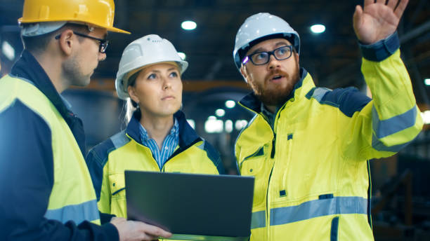 istock Male and Female Industrial Engineers Talk with Factory Worker while Using Laptop. They Work at the Heavy Industry Manufacturing Facility. 879813886