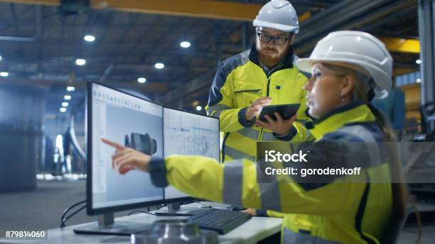 Photo libre de droit de À Lintérieur De Lusine De Lindustrie Lourde Femme Ingénieure Industriel Travaille Sur Ordinateur Personnel Elle Designs 3d Turbine Modèle Son Collègue Masculin Sentretient Avec Lui Et Utilise Le Tablet Pc banque d'images et plus d'images libres de droit de Ingénieur