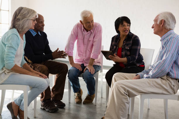 istock Senior friends discussing over tablet computer while sitting on chair 879825366