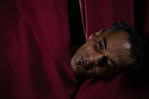 Close-up of ballet dancer peeking through a stage curtain
