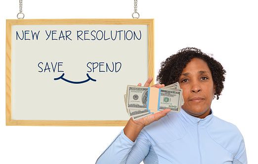 Woman holding one hundred dollar bills us currency looking at camera serious face New Year Resolution white board with save /spend on white background