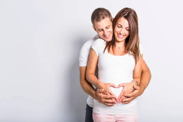 A caucasian couple expecting baby smiling cheerful on white