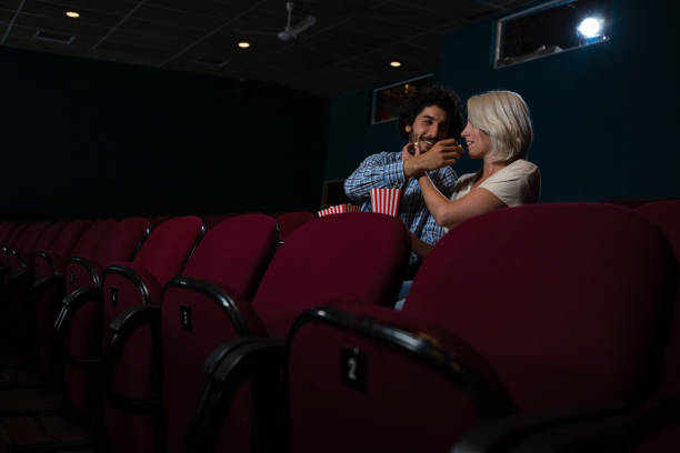 istock Couple having popcorn while watching movie in theatre 879836954