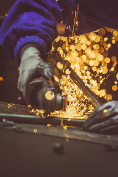 istock Creative and colored, vertical image of man working with steel pipe, producing golden sparks on the work surface. 879842430