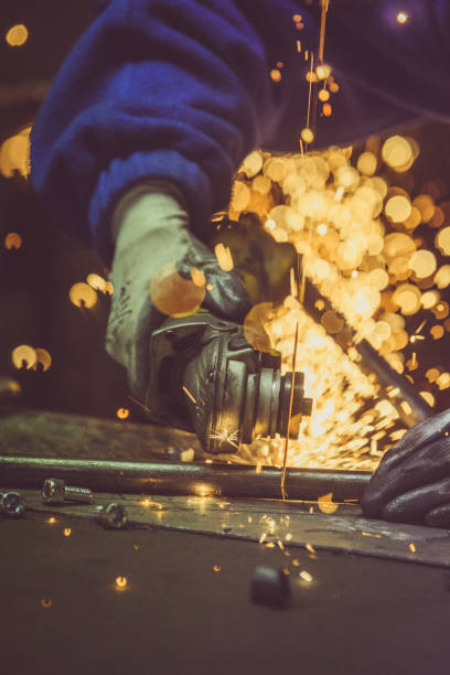 istock Creative and colored, vertical image of man working with steel pipe, producing golden sparks on the work surface. 879842432