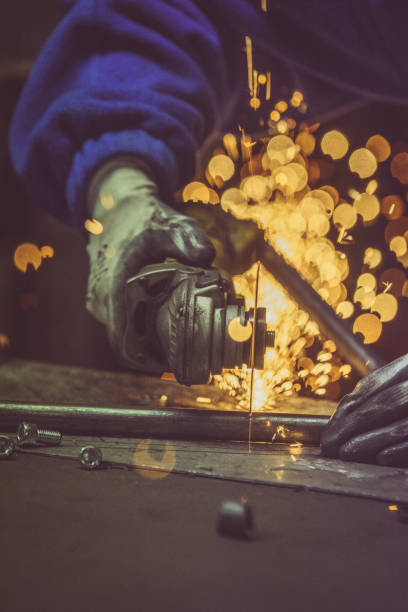 istock Creative and colored, vertical image of man working with steel pipe, producing golden sparks on the work surface. 879842600