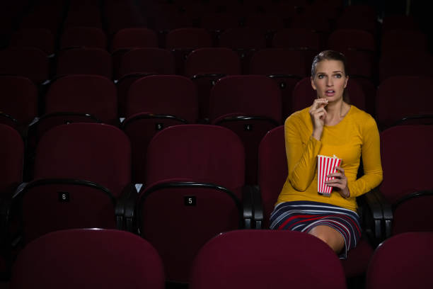 istock Woman having popcorn while watching movie in theatre 879845090