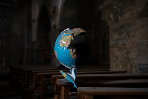 Qaraqosh, Iraq - May 20, 2017: A damaged globe, a remnant of ISIS destruction during its two-year occupation of the Church of the Immaculate Conception in Qaraqosh from 2014 to 2016, sits atop a pew.