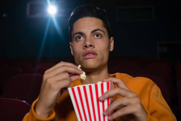 istock Man having popcorn while watching movie in theatre 879845684