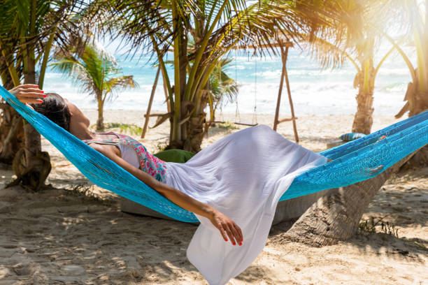istock Woman relaxing in a hammock on a tropical beach 879848692