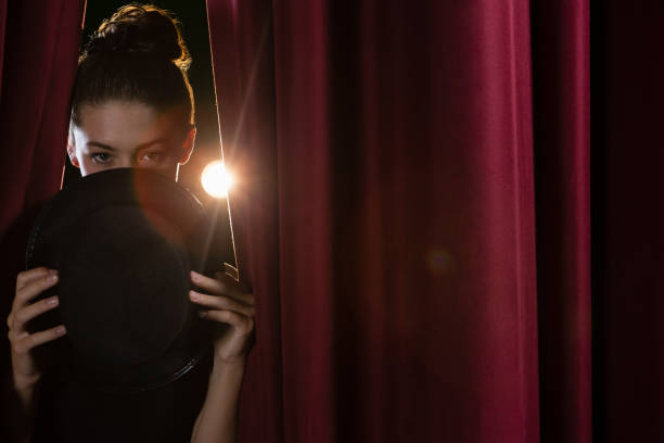 istock Ballet dancer with hat peeking through a stage curtain 879849112