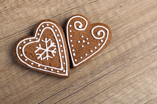 Two heart shaped gingerbread cookies on a wooden table.