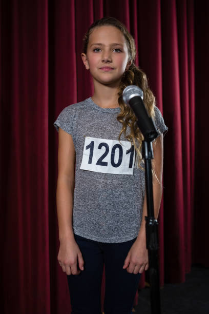 istock Girl standing front of microphone on stage 879878994