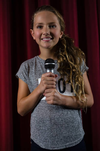 istock Girl holding microphone on stage 879879052