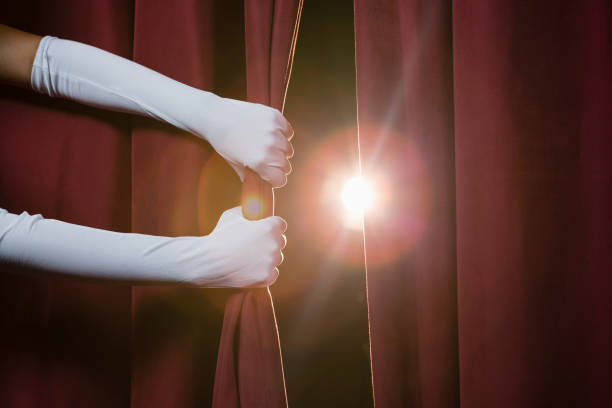 Hand in a white glove pulling curtain away stock photo