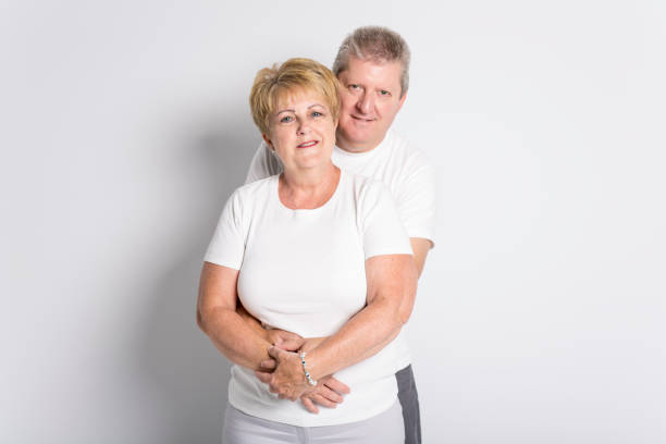 istock Happy smiling senior couple standing together on white background 879902148