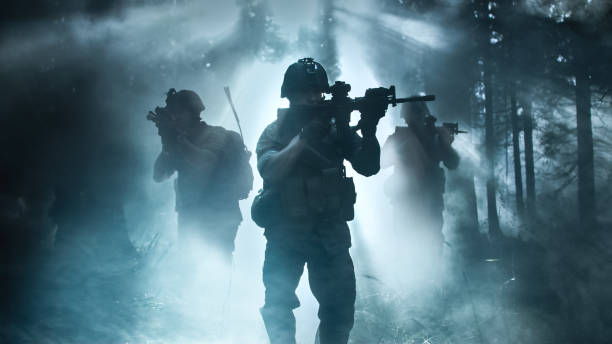 Silhouette of the Fully Equipped Soldier Moving Through Smokey Forest with Rifle Ready To Shoot. Reconnaissance Military Operation. Squad Moving Behind Him. Dark and Cold Ambient. Silhouette of the Fully Equipped Soldier Moving Through Smokey Forest with Rifle Ready To Shoot. Reconnaissance Military Operation. Squad Moving Behind Him. Dark and Cold Ambient. sniper stock pictures, royalty-free photos & images