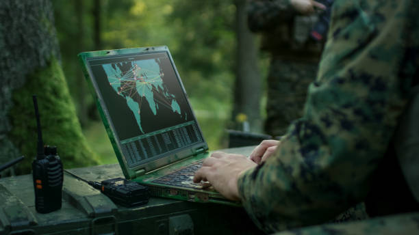 military operation in action, soldiers using military grade laptop targeting enemy with satellite. in the background camouflaged tent on the forest. - exército imagens e fotografias de stock