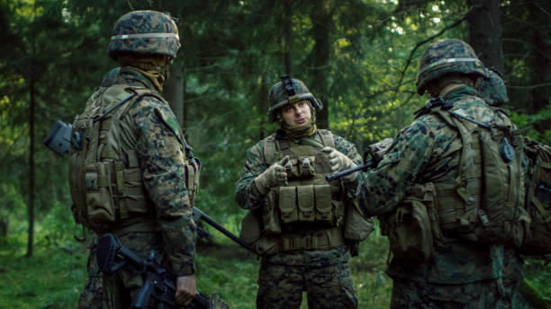 istock Squad Leader Discusses Military Operation Details with Soldiers, Commander Gives Orders. Fully Equipped and Armed Soldiers Ready for Mission in a Dense Forest. 879913178